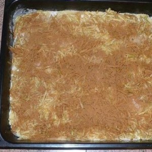 Cesto rozdelíme na dve polovice a vyvaľkáme na veľkosť plechu. 1. plát opatrne preložíme na dobre vymastený plech. Rovnomerne naň rozvrstvíme jablká ochutené kryštálovým, vanilínovým a škoricovým cukrom. Prikryjeme 2. plátom cesta. Okraje dobre pritlačíme.