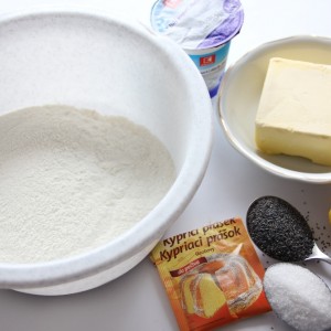 Pripravíme si suroviny. V mise zmiešame múku, kypriaci prášok do pečiva, soľ, cukor, mak a kôru z citróna. Pridáme maslo a jogurt a spracujeme cesto, ktoré dáme na 30 minút do chladničky.