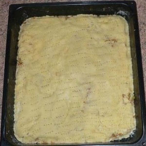 Celý povrch koláča popicháme vidličkou. Dáme piecť do vyhriatej rúry.  Upečený koláč posypeme škoricovým cukrom a pokrájame na kocky a možeme podávať.